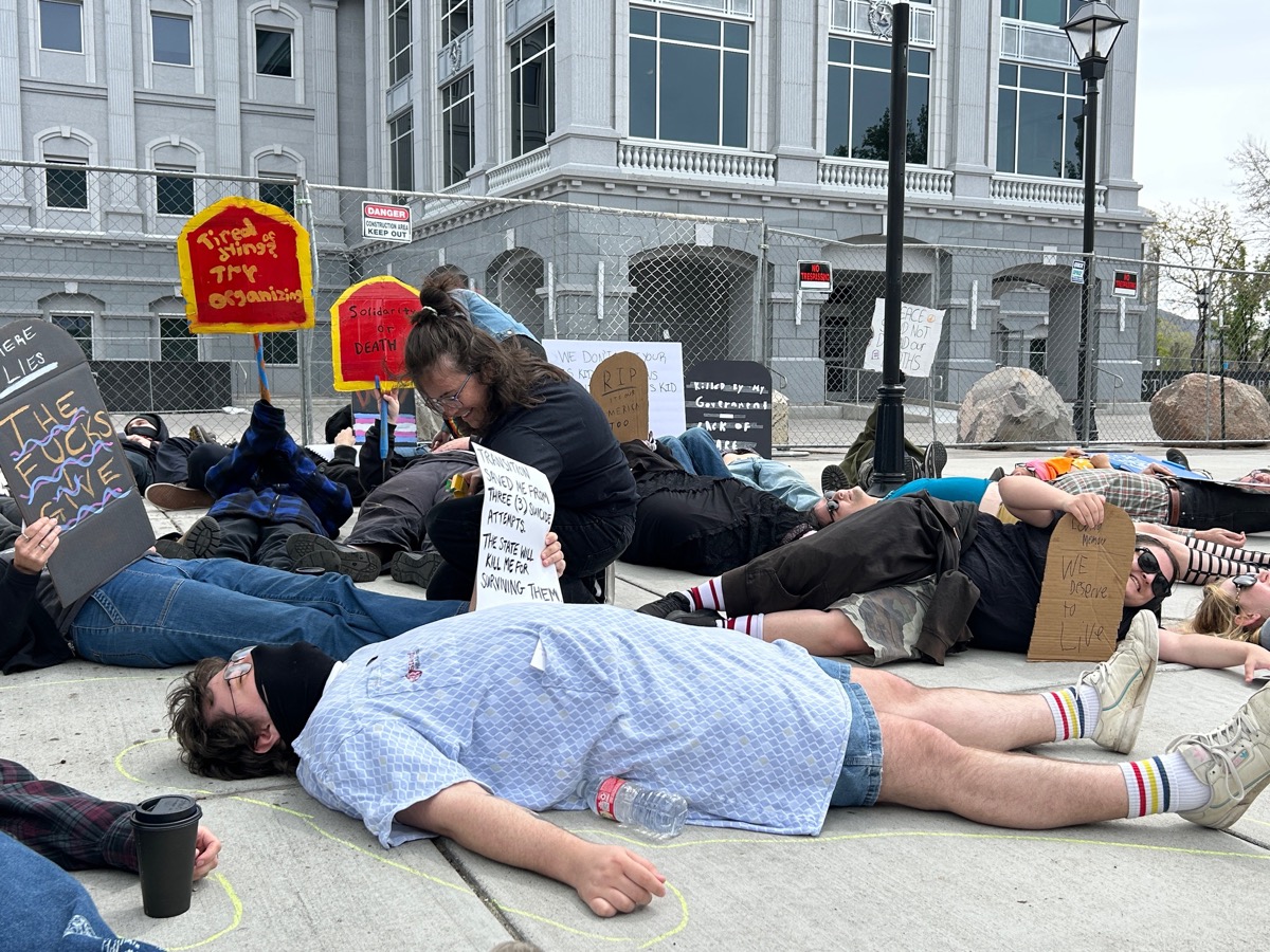 Die-in participants with protest signs at the State Senate